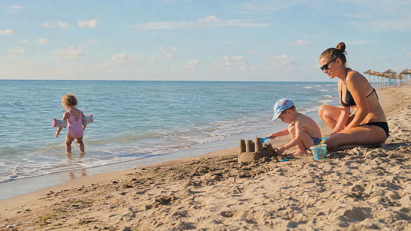 Mother and children enjoying the sandy beach in Golem, Albania.