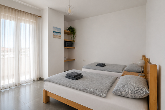 Ložnice se dvěma samostatnými lůžky a balkonem v apartmánu Pushim