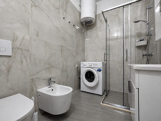Koupelna se sprchovým koutem, bidetem a pračkou v apartmánu Pushim