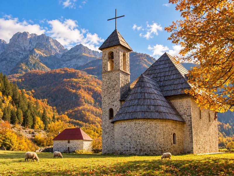 Small church beneath the night sky and mountains in Albania